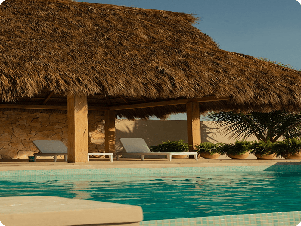 A thatched poolside pavilion beside clear turquoise water
