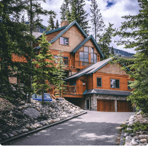 A timber vacation home surrounded by tall evergreen trees
